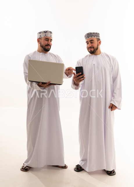 رجال عمانيون يستخدمون الحاسوب والهاتف في الاستوديو