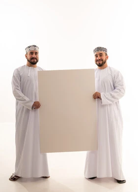 رجلان عُمانيان يمسكان بلوحة إعلانية بيضاء فارغة