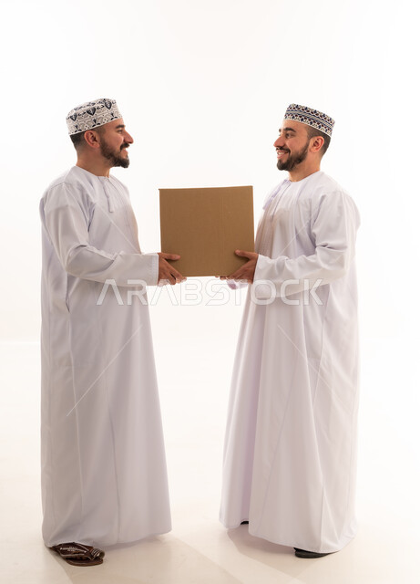 رجلان عمانيان بالزي التقليدي يحملان صندوق شحن
