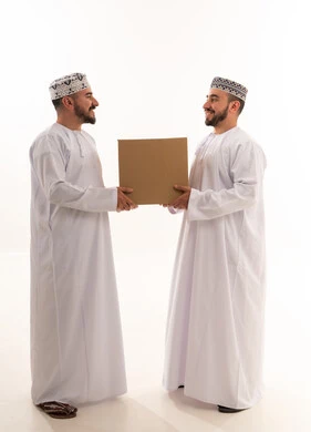 رجلان عمانيان بالزي التقليدي يحملان صندوق شحن