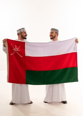 رجال عمانيون بالزي التقليدي يحملون علم سلطنة عمان