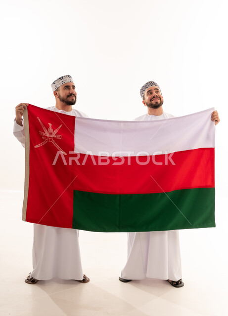 رجال عمانيون يحملون علم سلطنة عمان باللباس التقليدي