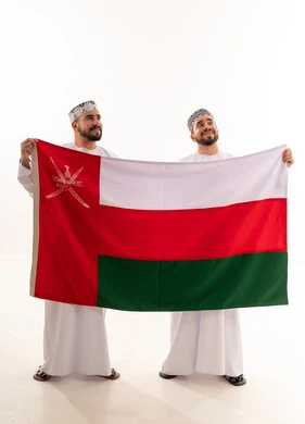 رجال عمانيون يحملون علم سلطنة عمان باللباس التقليدي