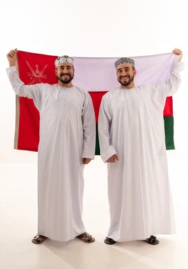 رجال عمانيون بالزي التقليدي يحملون علم سلطنة عمان