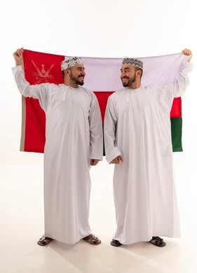 رجال عمانيون باللباس التقليدي يحملون علم سلطنة عمان