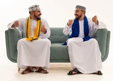 Two Omani Men in Traditional Dress Cheering on Sofa
