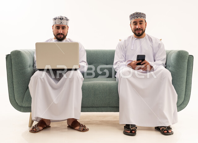 Omani Men with Laptop and Smartphone on Sofa