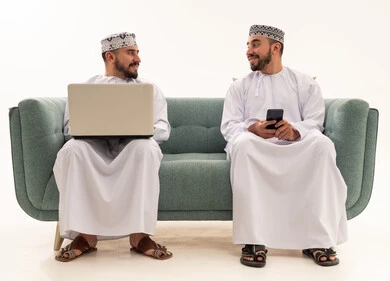 Omani Men with Laptop and Smartphone on Sofa