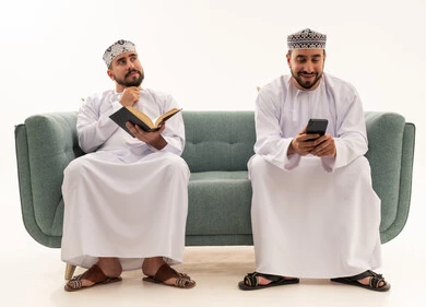 Omani Men in Traditional Dress with Book and Smartphone