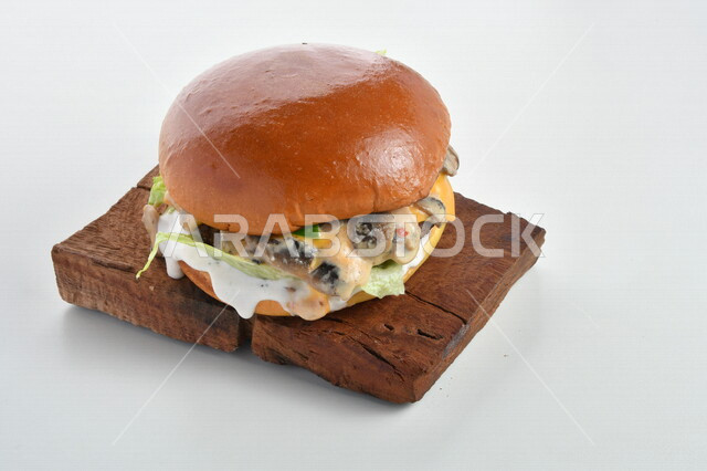 Close-up of a delicious hamburger sandwich stuffed with meat, cheese, lettuce and different flavors, delicious burger meal pictured on a white background, fast food, Arabic restaurants, delicious food