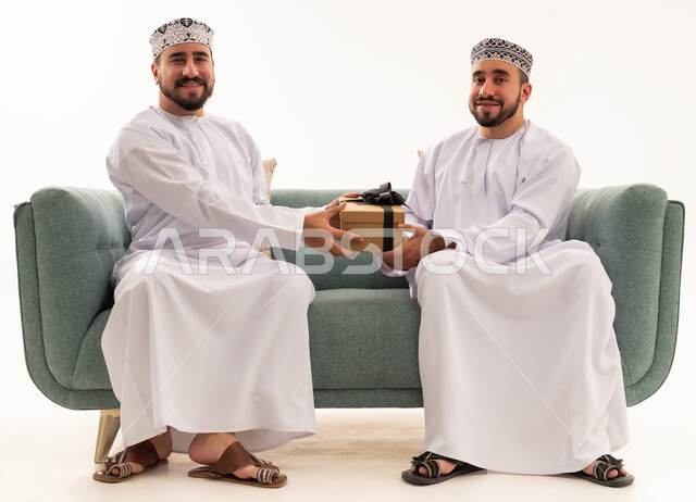 رجلان عمانيان يتبادلان الهدايا في استوديو خلفية بيضاء