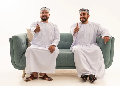 رجال عمانيون بإيماءة الإبهام للأعلى على الأريكة