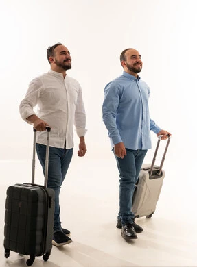 رجال سعوديون يسيرون بحقائب سفر على خلفية بيضاء