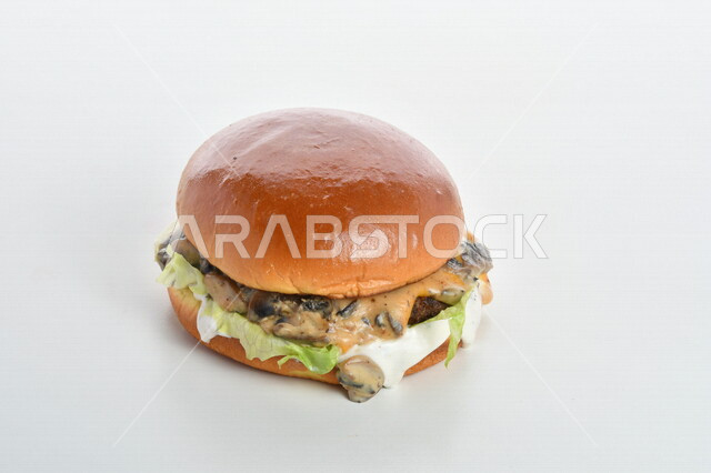 Close-up of a delicious hamburger sandwich stuffed with meat, cheese, lettuce and different flavors, delicious burger meal pictured on a white background, fast food, Arabic restaurants, delicious food