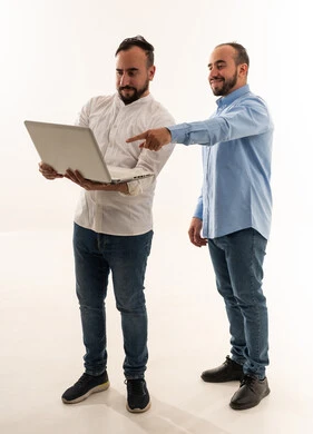رجلان سعوديان يستخدمان حاسوب محمول بخلفية بيضاء