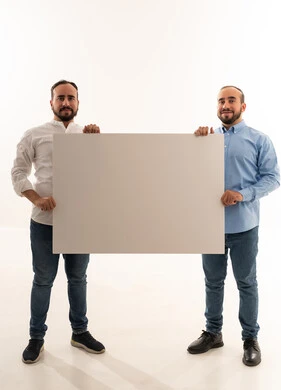 رجلان سعوديان يحملان لوحة بيضاء فارغة في استوديو