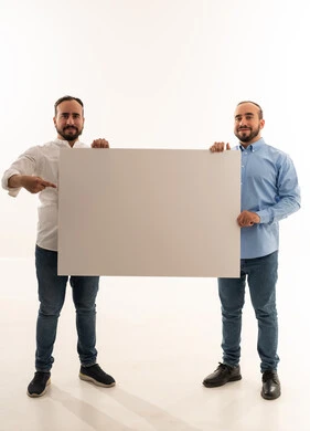 رجلان سعوديان يحملان لوحة بيضاء فارغة مخصصة للإعلانات
