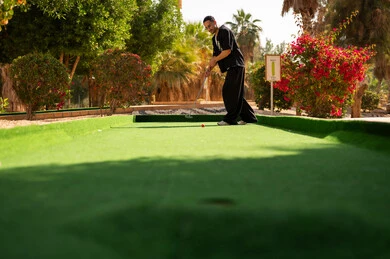 Saudi Man Playing Mini Golf on Green Outdoor Course