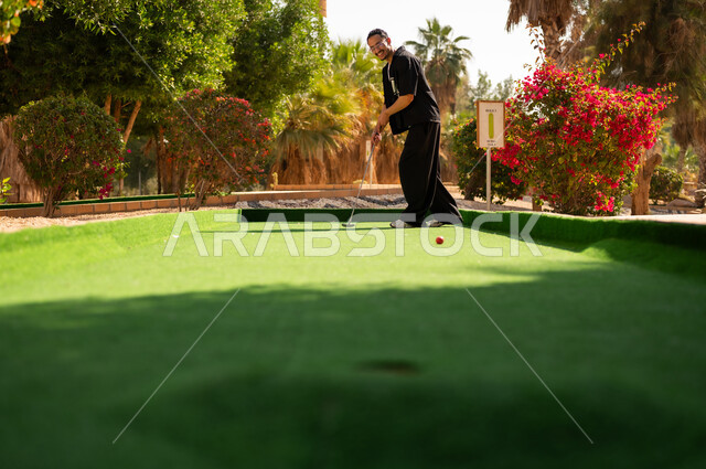 Saudi Man Playing Mini Golf Outdoors in Daylight