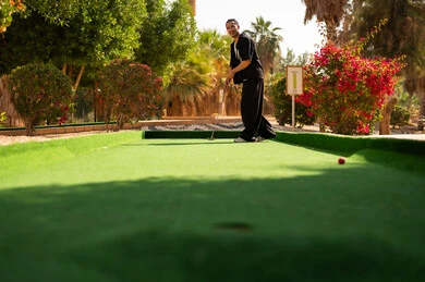 رجل سعودي يلعب الميني غولف في حديقة مشمسة