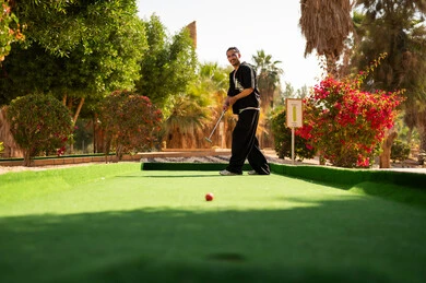 رجل عربي يلعب الميني غولف في حديقة خارجية