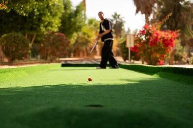 رجل عربي يلعب الميني غولف في ملعب خارجي