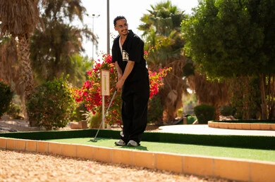 شاب عربي يلعب الميني غولف في ملعب خارجي