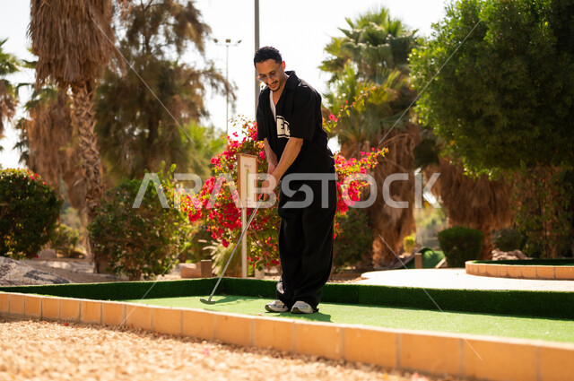 شاب سعودي يلعب الميني جولف في منطقة ترفيهية