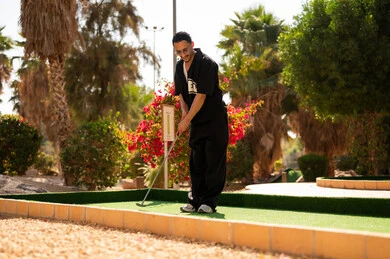 شاب سعودي يلعب الميني جولف في منطقة ترفيهية