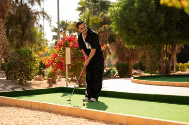 شاب سعودي يلعب ميني غولف في ملعب خارجي