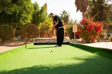 رجل سعودي يلعب الميني غولف في منتزه خارجي