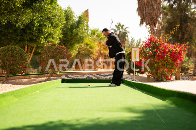 Saudi Man Playing Mini Golf at Outdoor Resort