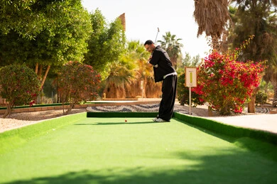 رجل سعودي يلعب الميني غولف في منتجع خارجي