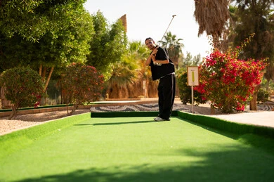 رجل عربي يلعب الميني غولف في الهواء الطلق