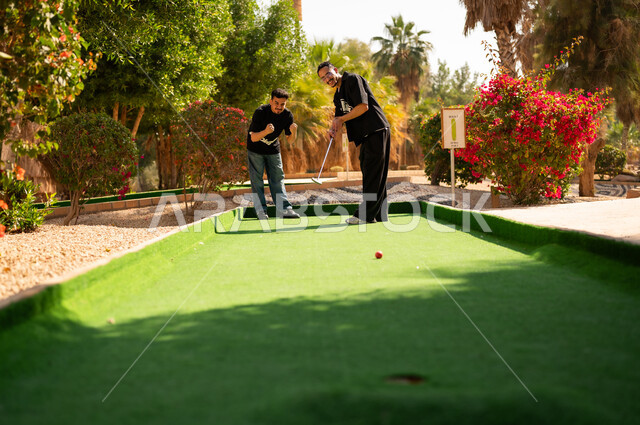 Arab Men Playing Mini Golf at Outdoor Recreation Park