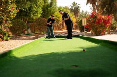 رجال سعوديون يلعبون الميني غولف في حديقة خارجية