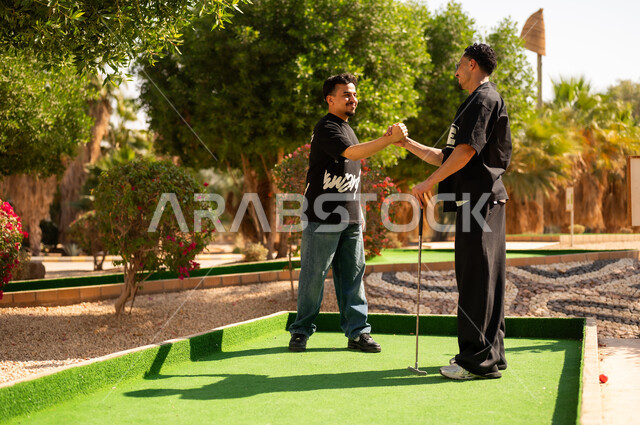 Saudi Men Shaking Hands Playing Mini Golf Outdoors