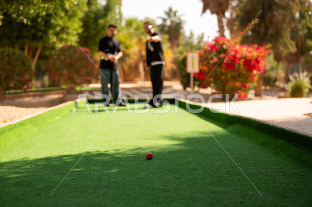 Arab Men Playing Mini Golf on Outdoor Green Course