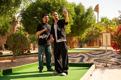 رجال عرب يلعبون الميني غولف ويلتقطون سيلفي