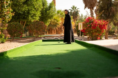 امرأة سعودية تلعب الميني جولف في حديقة خارجية