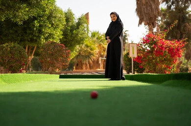 امرأة سعودية تلعب الميني غولف في حديقة خارجية