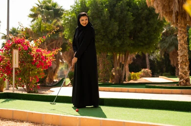 امرأة سعودية تلعب الميني غولف بالعباءة السوداء