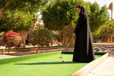 امرأة عربية تلعب الميني غولف بالعباءة السوداء