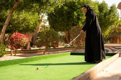امرأة سعودية تلعب الغولف المصغر في حديقة خارجية