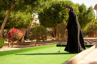 امرأة سعودية تلعب الميني غولف بالعباءة السوداء