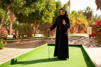 Emirati Woman in Abaya Playing Mini Golf Outdoors