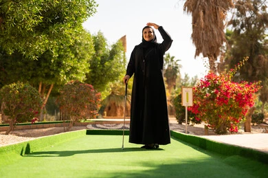 امرأة سعودية بالعباءة في ملعب جولف خارجي