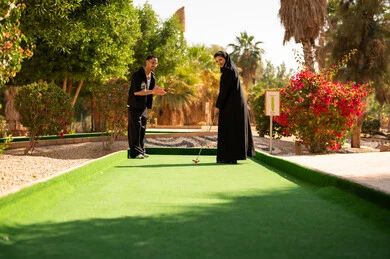 زوجين سعوديين يلعبان الميني غولف في حديقة ترفيهية خارجية