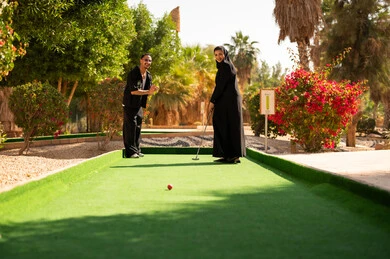 زوجان سعوديان يلعبان الميني غولف في حديقة خارجية