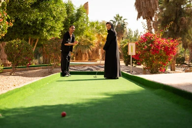 زوجان سعوديان يلعبان الجولف المصغر في منتزه خارجي